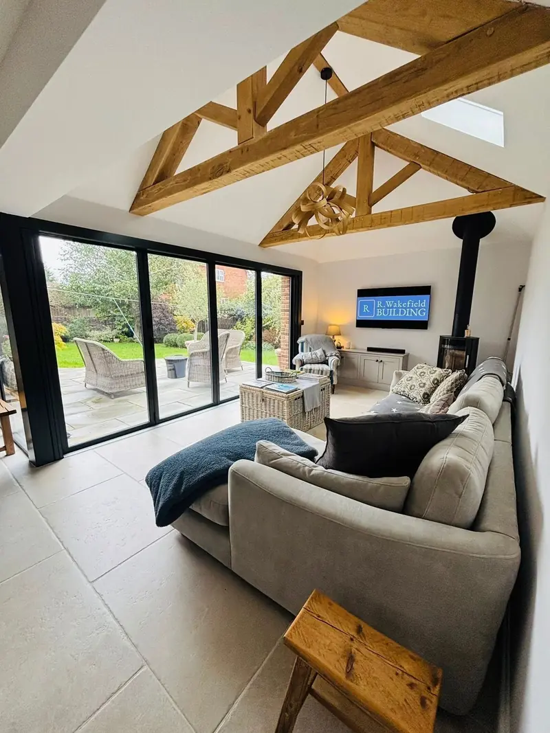Handmade oak king post trusses under a vaulted ceiling with a rooflight, above a wood burning stove
