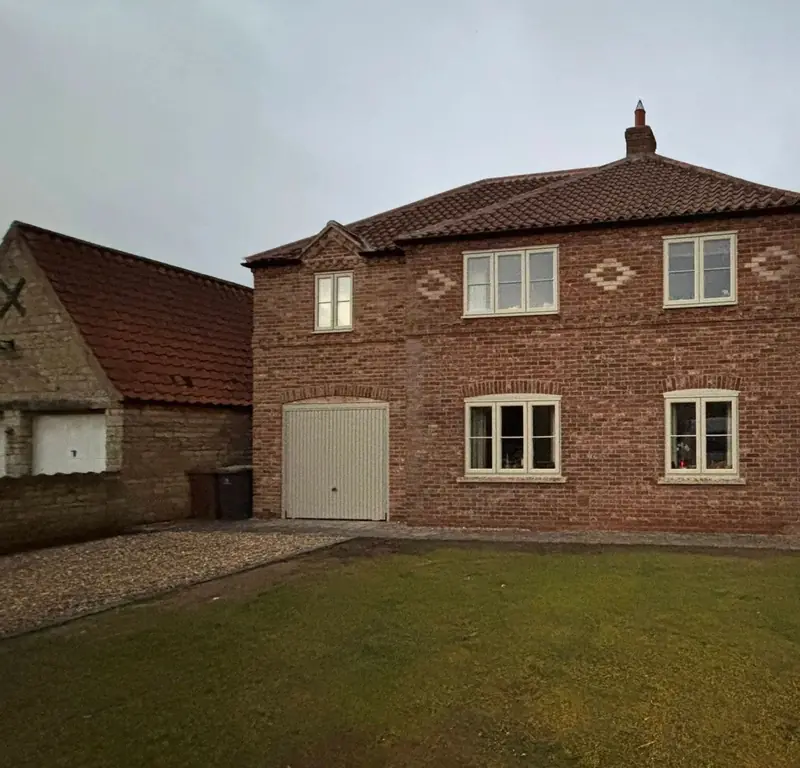 Two-storey red brick extension with cream windows, decorative brick diamonds and a garage door