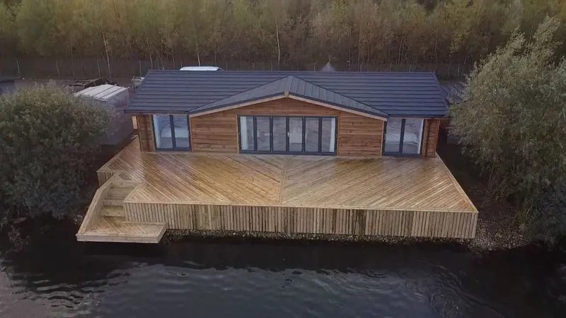 Timber-clad lodge with a wide timber deck over the water, seen from above