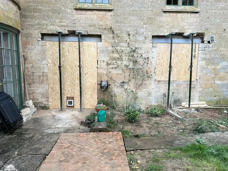 Before: two openings in an old limestone wall, boarded up and held on steel props